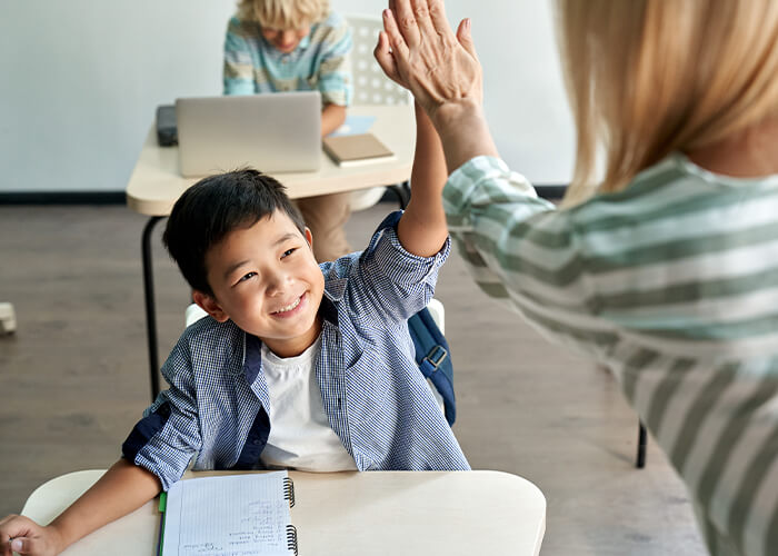 Elementary students high fiving his teacher